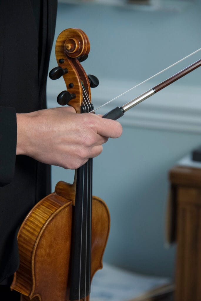 Violinist holding instrument by neck with bow in hand